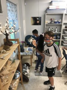 Second graders in the science classroom near artifacts on a shelf