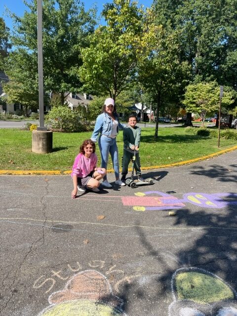 A family stands near a chalk art drawing of Pete the Cat.