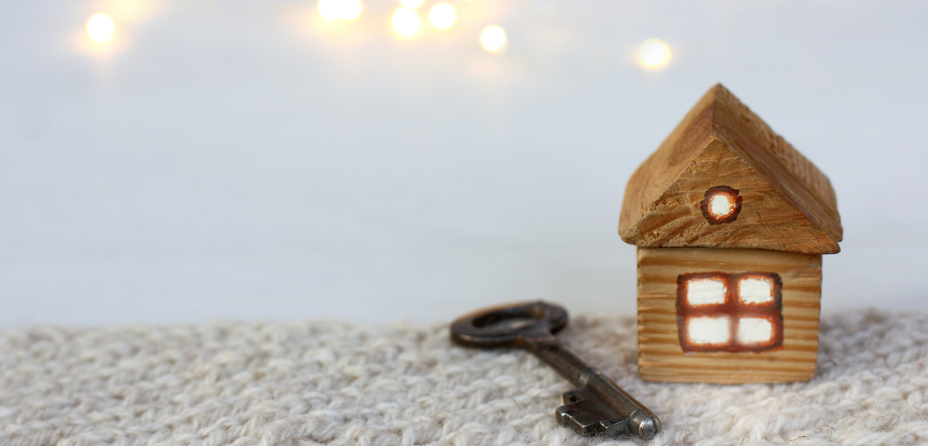 a small house figurine with light on inside with white lights and a key in the background